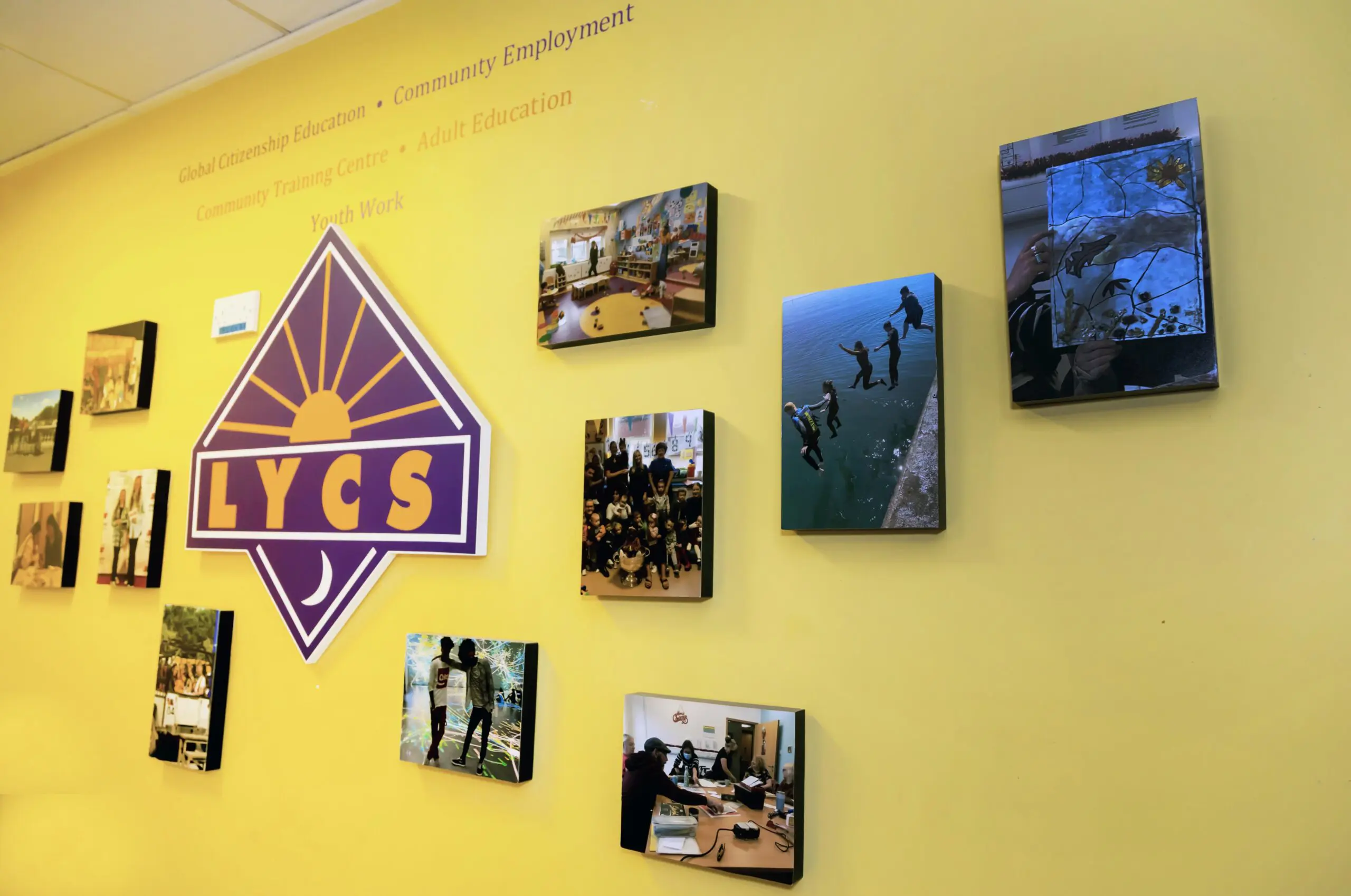 The LYCS logo surrounded by photographs of activities in LYCS. Above the logo reads: Global Citizenship Education, Community Employment, Community Training Centre, Adult Education, Youth Work. Photographed by Paul Reardon.