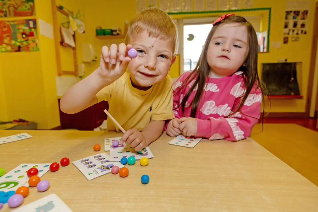 2 of our creche learners show off some coloured balls to the camera, smiling brightly. Photographed by Paul Reardon.